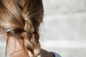 Otwarty róż w kompakcie z pędzlem na marmurowym blacie, w tle inne odcienie różu – eleganckie kosmetyki do makijażu.